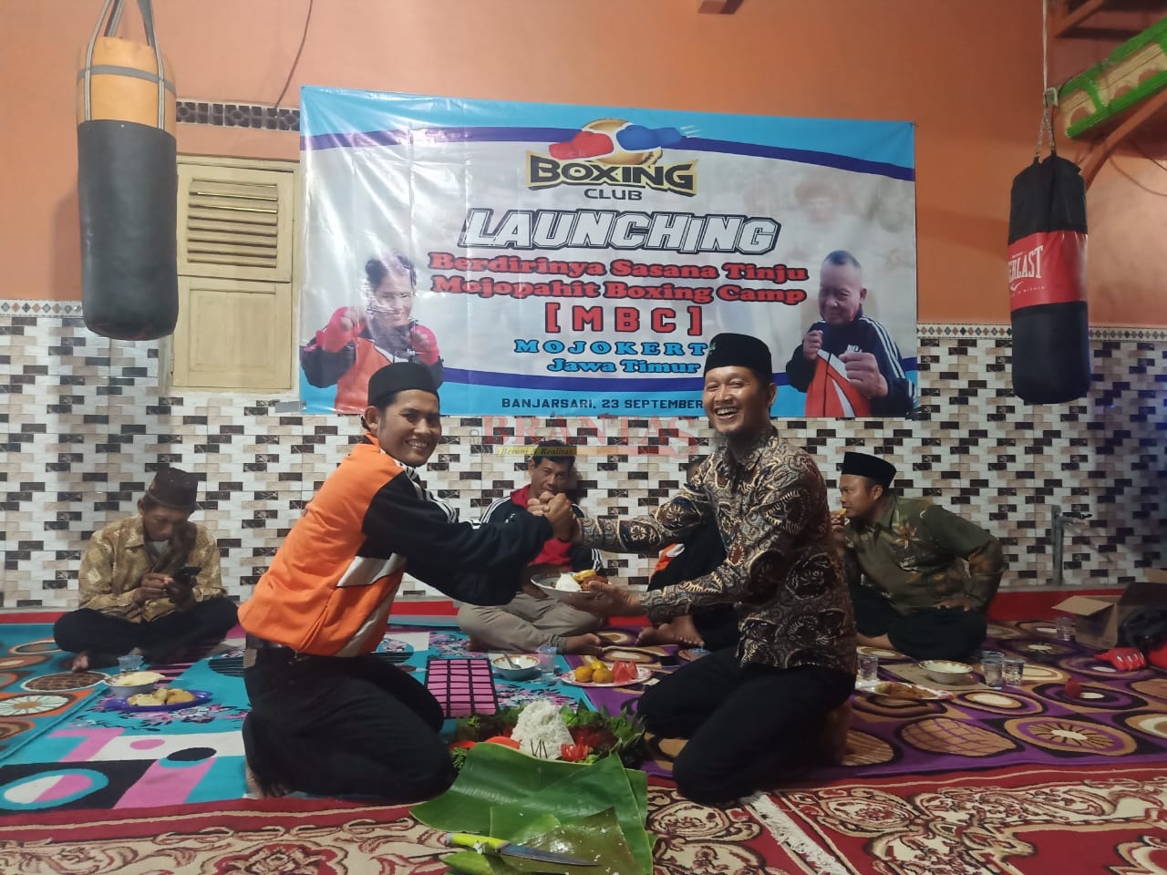 Manager Sasana Tinju MBC Mojokerto Kartono memberikan potongan tumpeng Kepada Kades Banjarsari Subagio sebagai Tanda Tasyakuran Launching