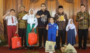 PJ. Walikota Mojokerto Ali Kuncoro didampingi Kadis P & K Kota Mojokerto Ruby Hartoyo menyerahkan secara simbolis perlengkapan sekolah kepada siswa