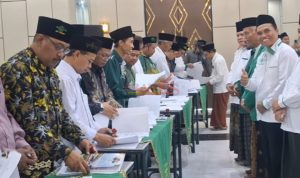 H. Khoirul Amin, S.Sos, ( kanan ) Ketua Pengadaan Mobil Layanan Umat menyaksikan Ketua MWCNU Pungging KH. Afan Faizin, M.Pd, menandatangani berita acara
